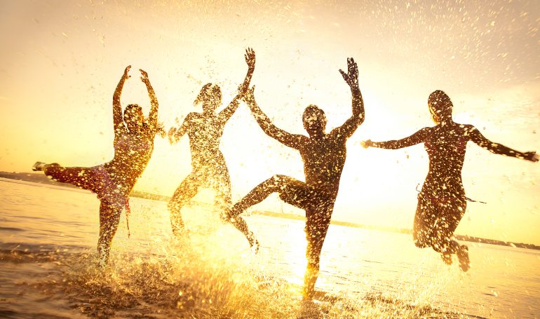 Silhouetted friends enjoy sunset splashing in ocean water