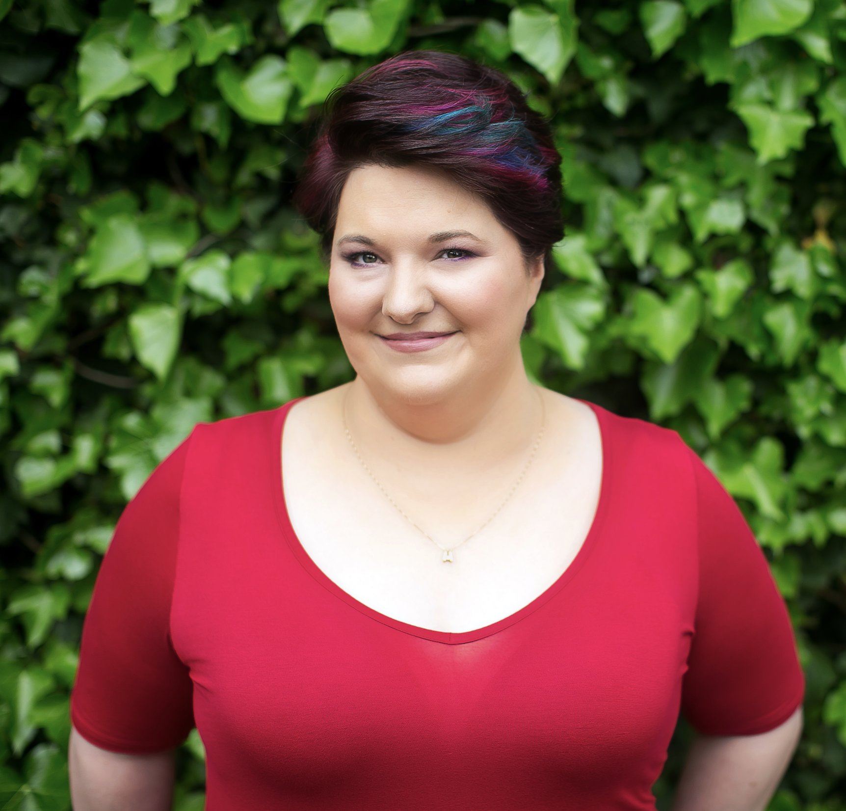 Woman in red top against green leafy background