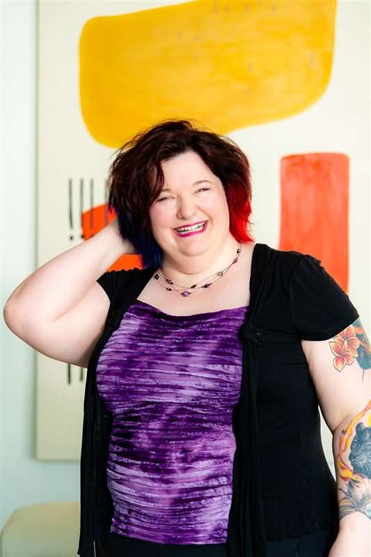Woman smiling with colorful artwork in the background