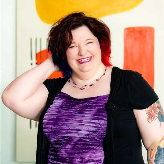 Woman smiling with colorful artwork in the background