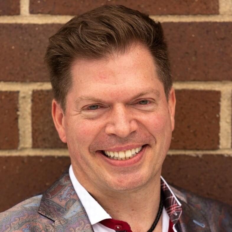 Smiling man in stylish jacket against brick wall backdrop