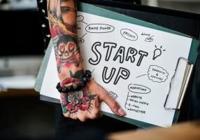 Person with tattoos holding a startup brainstorming clipboard