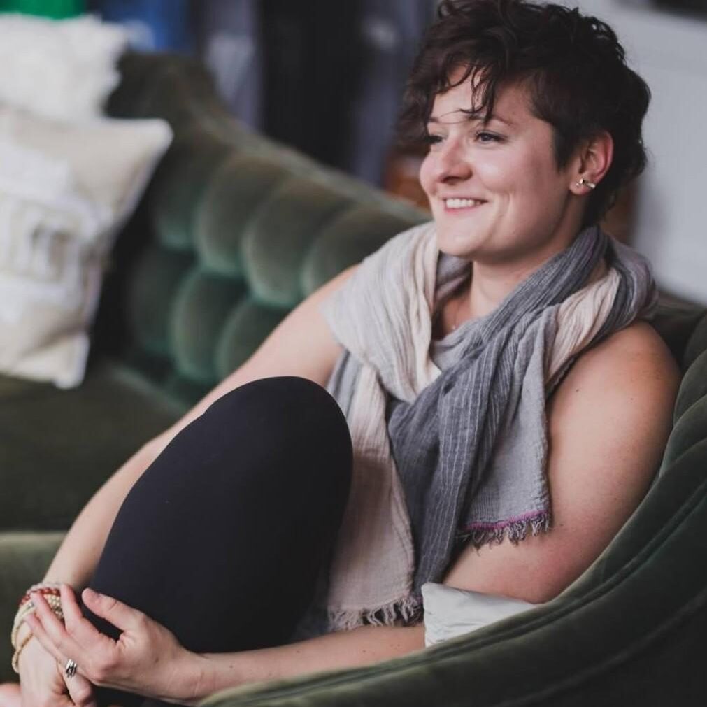 Smiling woman relaxing on a green couch with cozy throw pillows